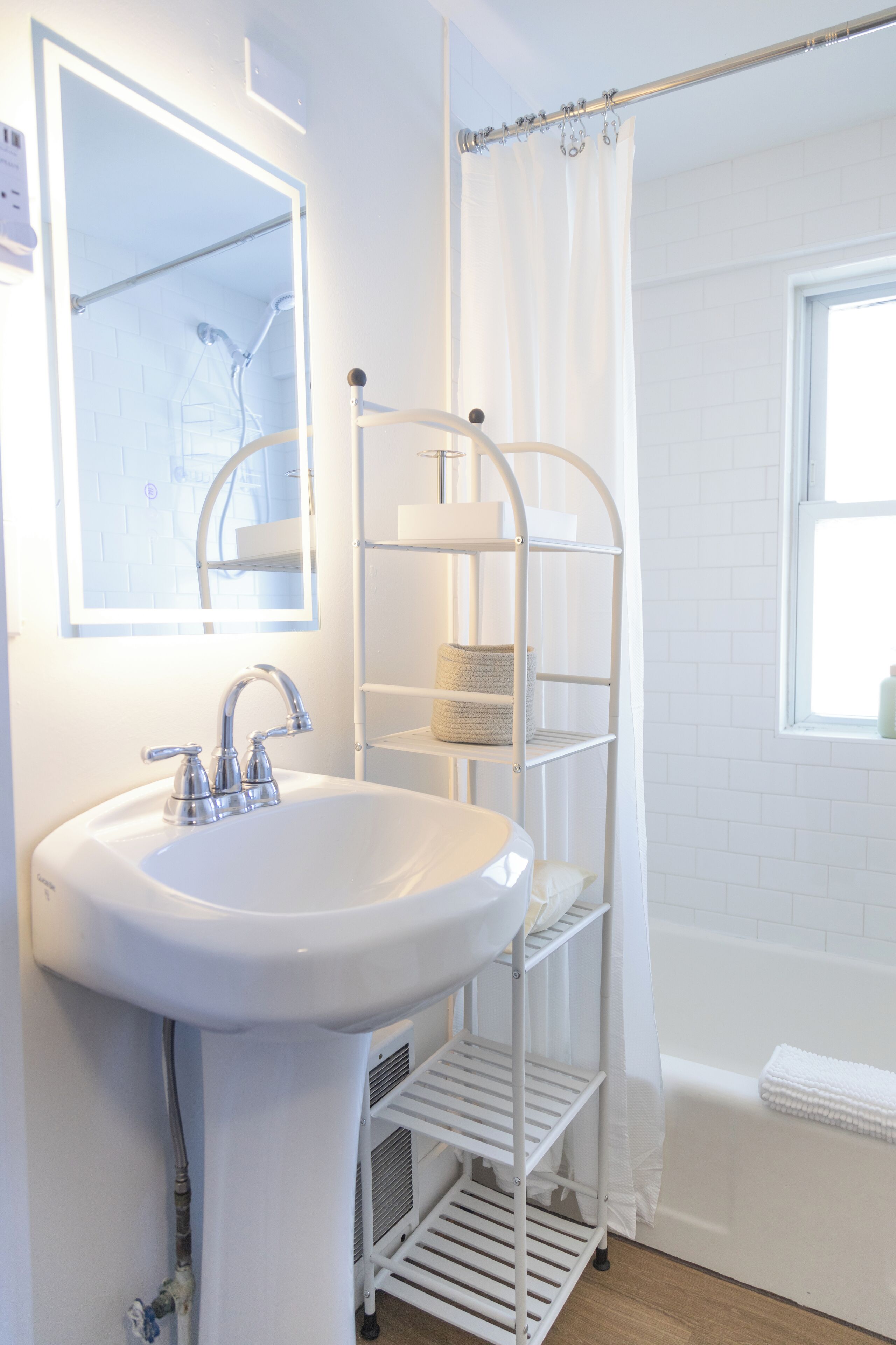 A bathroom with a white sink, a mirror, a shower curtain, and a window.