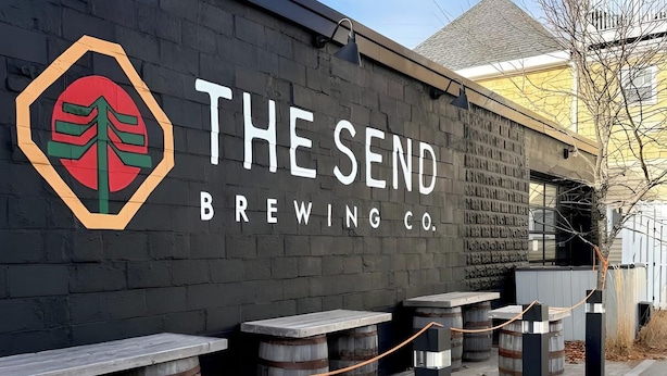 Un edificio con un letrero que dice "The Send Brewing Co." y un logotipo con un árbol estilizado.