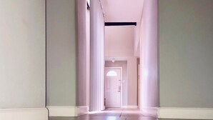 Um corredor comprido e estreito com chão de azulejos e paredes brancas.