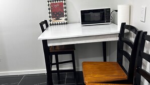 A dining area with a white table, black chairs, a wooden bench, a microwave, and a wall-mounted light switch. - Private basement apartment in private house in vibrant Minneapolis (Minneapolis)