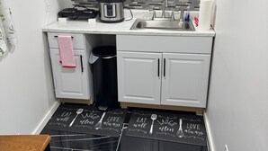 A compact kitchen with white cabinets, a black countertop, a sink, a kettle, and a trash bin. - Private basement apartment in private house in vibrant Minneapolis (Minneapolis)