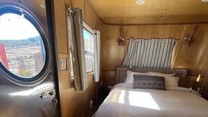 Un dormitorio pequeño con cama, ventana, cortinas y puerta.
