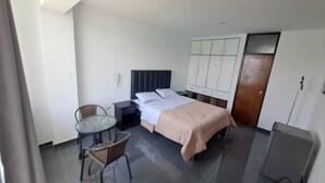 A hotel room with a bed, a small table with chairs, a wardrobe, and a door. - HOTEL KENDARI (Grocio Prado)