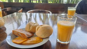 A table with a plate of food and a glass of orange juice. - HOTEL KENDARI (Grocio Prado)