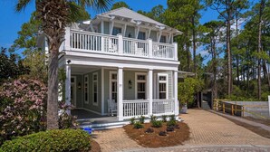 A two-story house with a balcony, a porch, and a brick pathway leading to the entrance. - 30A Stay With Pool & Beach Access + Free Attraction Tickets! (Santa Rosa Beach)