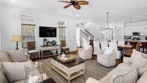 A spacious living room with a large TV, comfortable seating, a dining area, and a kitchen. - 30A Stay With Pool & Beach Access + Free Attraction Tickets! (Santa Rosa Beach)