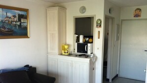 A compact kitchen with a white cabinet, a coffee maker, and a microwave. - Rent apartment in la grande Motte, couchant district with air conditioning (La Grande-Motte)
