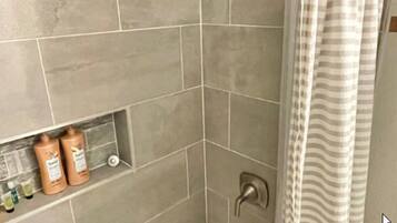 Un baño con ducha, bañera y retrete. Hay artículos de aseo en la pared.