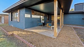 A building with a covered patio area, a brick exterior, and a window with a sign.
