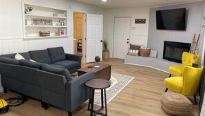 A living room with a sofa set, a coffee table, a yellow armchair, and a fireplace.