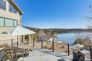 Eine Terrasse mit Gartenmöbeln, einem Grill und Seeblick.