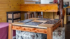 A rustic wooden interior with a high ceiling, exposed beams, and a central wooden table with menus. - Vivisierras Espectacular Cabaña Villa Carlos Paz pileta privada barrio exquisito (Villa Carlos Paz)