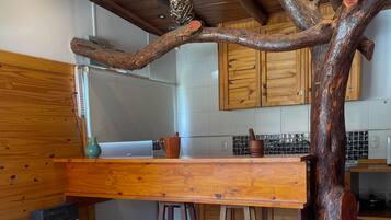 Une cuisine rustique avec des meubles de rangement en bois, une table à manger en bois et une structure originale faite de branches d’arbre.