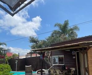 Enjoy a meal at this charming restaurant with a covered patio area and a small pool in the background.