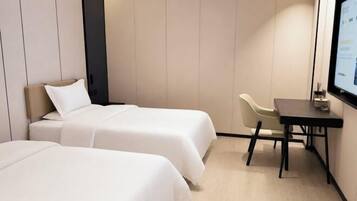 Habitación de hotel con dos camas, un escritorio y un televisor.