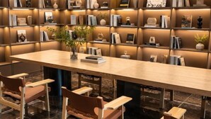 A modern library with a long table and chairs, surrounded by bookshelves. - Beijing Baishang Hotel (Beijing)