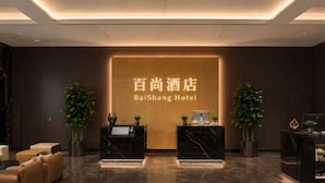 A hotel reception area with a marble floor, two reception desks, and a large sign displaying the hotel name. - Beijing Baishang Hotel (Beijing)