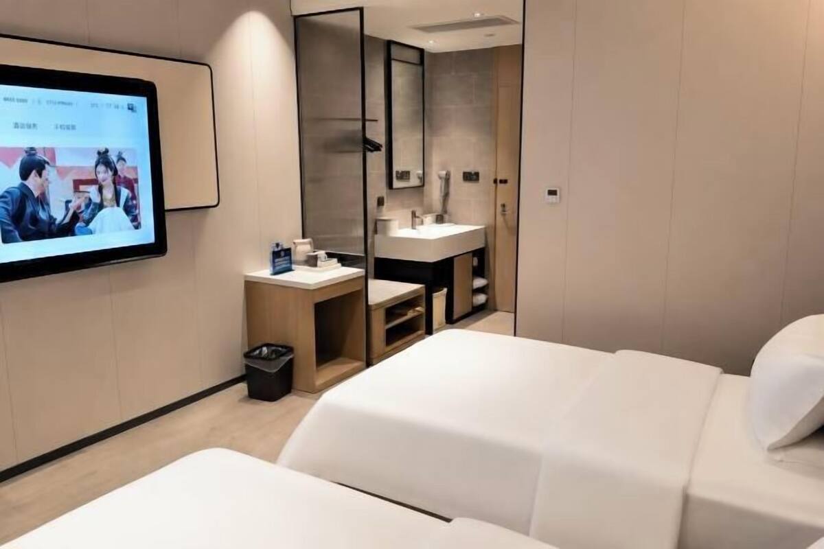 Ein Hotelzimmer mit Bett, Schreibtisch, Computer, Spiegel und Fernseher.