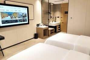 Quarto de hotel com uma televisão de tela grande, uma penteadeira de madeira com espelho, pia e uma cama.