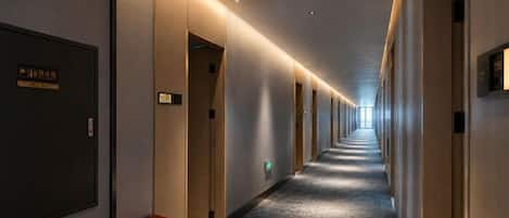 Pasillo de hotel con puertas a ambos lados, piso alfombrado y un letrero con los números de las habitaciones.