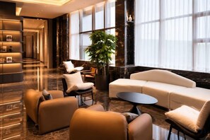 A modern lobby with a reception desk, seating area, and large windows. - Beijing Baishang Hotel (Beijing)