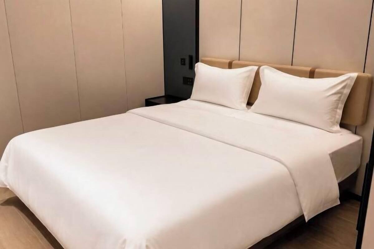 Ein ordentlich bezogenes Bett mit Kopfteil, Nachttisch und Wandverkleidung.