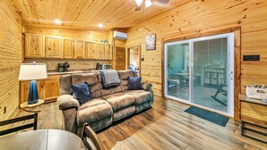 A cozy cabin interior with a wooden ceiling, a sofa, a dining table, and a kitchen area. - Pam's Treehouse Cabin #2-Your wonderful treehouse getaway...right on a creek! (Hot Springs)