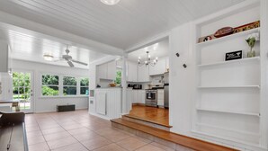 A spacious kitchen with white cabinetry, a built-in oven, and a microwave. There are wooden steps leading to a lower level, and a ceiling fan is visible. - Charming 3/2 Midtown Home. Minutes from FSU. Fenced Backyard. Pet-Friendly. (Tallahassee)