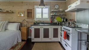 Cocina compacta con paredes de madera, una isla central, estufa y lavamanos.