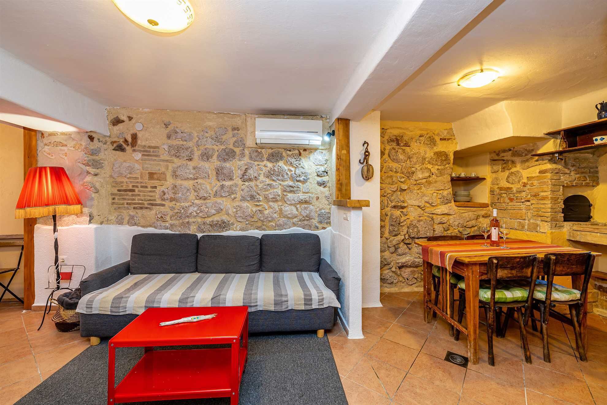 A cozy living room with a sofa, a red table, and a stone wall.