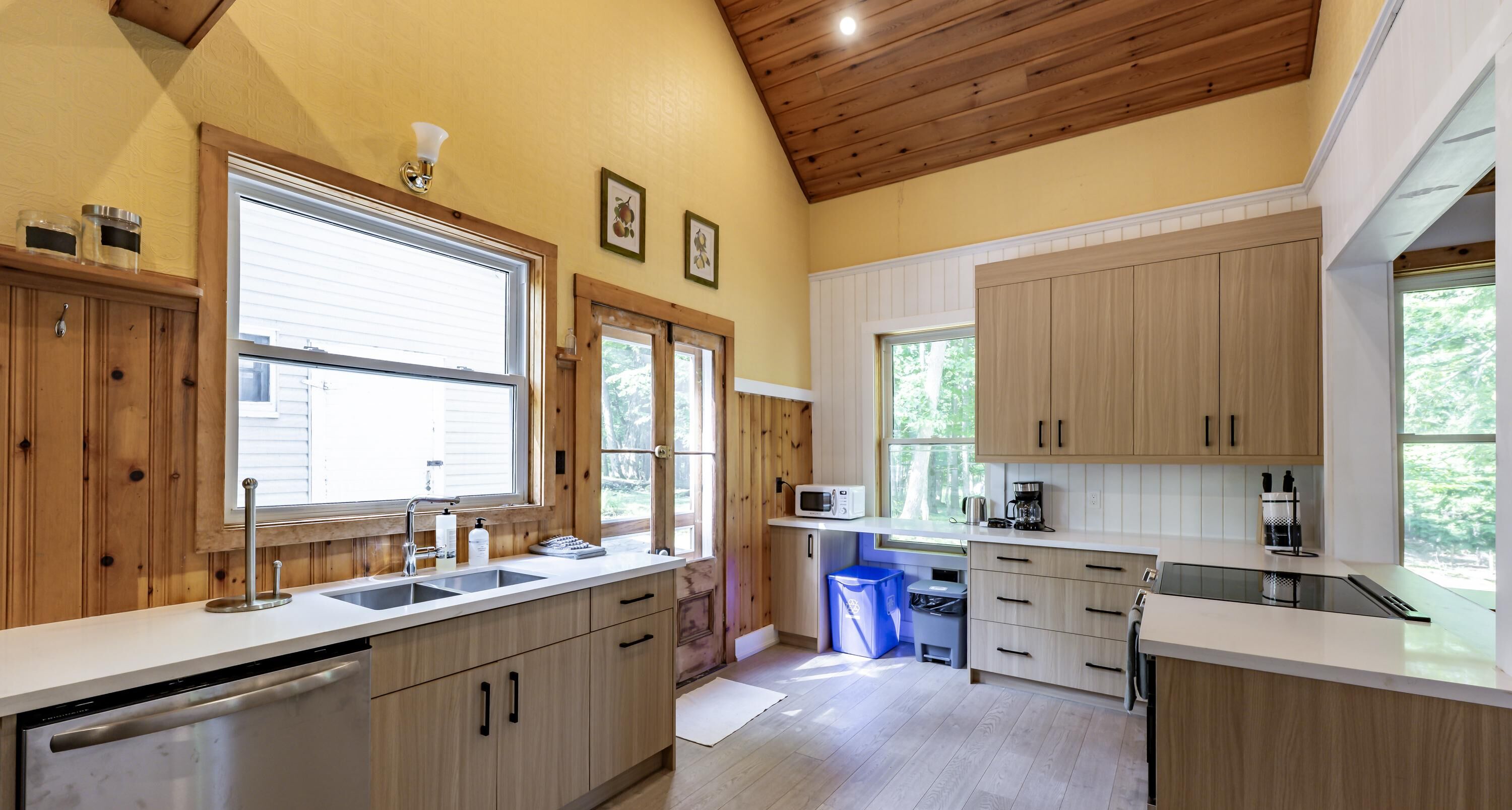 A modern kitchen with wooden cabinets, a dishwasher, a sink, and a microwave.
