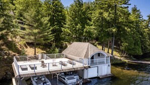 A lakeside cabin with a deck, dock, and boats.