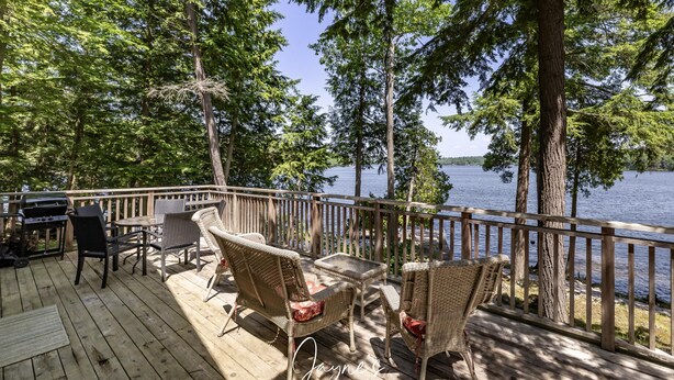 A wooden deck with wicker furniture overlooking a lake.