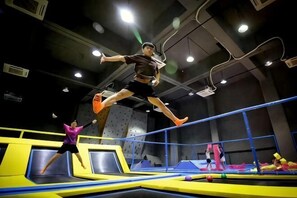 Un parc de trampolines intérieur comprenant plusieurs trampolines et des filets de sécurité.