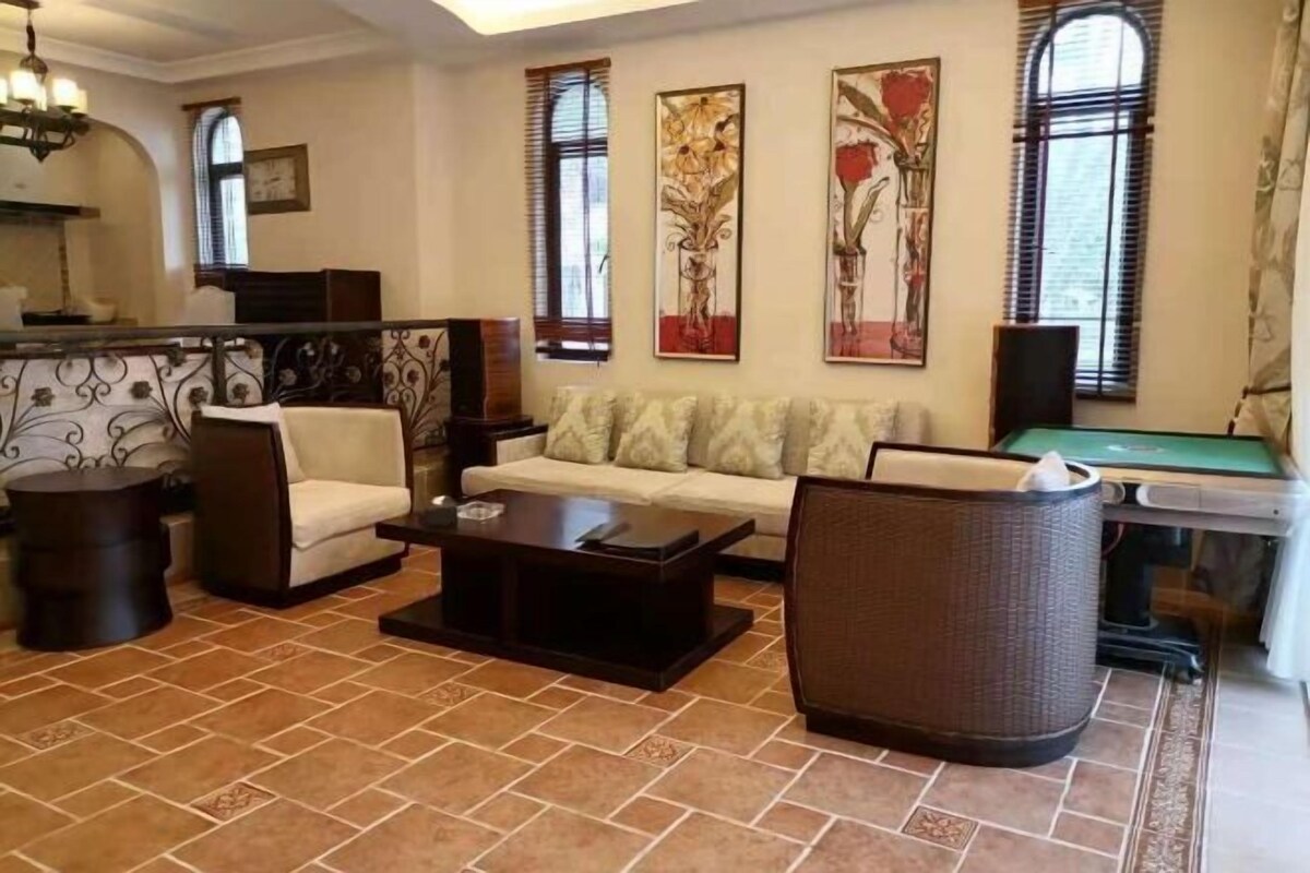 Un salon comprenant un canapé, des fauteuils, une table basse, une table de billard et des œuvres d’art accrochées aux murs.