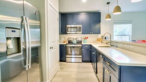 A modern kitchen with stainless steel appliances, dark blue cabinets, and a light-colored countertop.