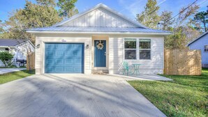 A single-story house with a blue garage door, a front porch with a bench, and a small garden area.