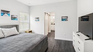 A modern bedroom with a bed, a TV, and artwork on the walls.