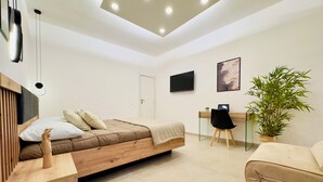 Une chambre à coucher moderne avec un lit, une table de chevet, un bureau, une chaise et une plante en pot.