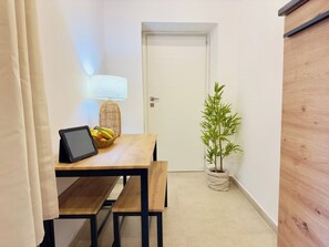 A small room with a wooden table, a laptop, a lamp, a potted plant, and a door.