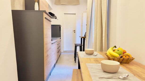 Une cuisine moderne avec un plan de travail en bois, un saladier, une cuillère et un panier de fruits.
