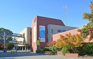 Ein Gebäude mit auffälligem Arts & Science Schild, einem Picknicktisch und blauem Himmel.