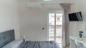 Una camera da letto con un letto, un comodino, una TV e un balcone con vista.