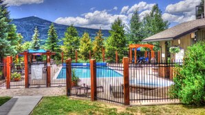 Un patio trasero con piscina, pérgolas de madera y montañas al fondo.