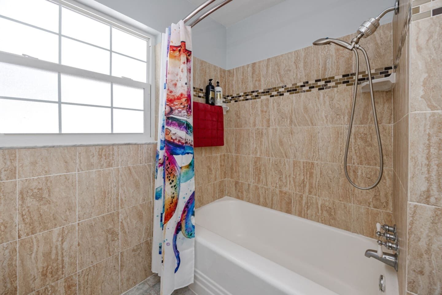 Un baño con bañera, ducha y ventana.