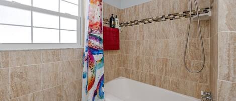 Un baño con bañera, ducha y ventana.