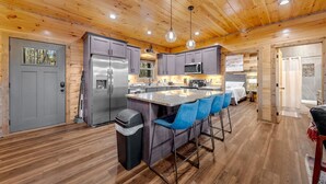 A modern kitchen with wooden ceiling, stainless steel appliances, and a central island with bar stools. - Spacious 5-bedroom cabin in marvelous Pigeon Forge with AC, WiFi (Pigeon Forge)