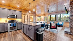 A spacious kitchen with modern appliances, a large island, and a cozy seating area with a stone fireplace. - Spacious 5-bedroom cabin in marvelous Pigeon Forge with AC, WiFi (Pigeon Forge)