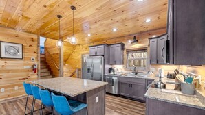 A modern kitchen with granite countertops, stainless steel appliances, and a central island with bar stools. - Spacious 5-bedroom cabin in marvelous Pigeon Forge with AC, WiFi (Pigeon Forge)