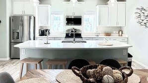 A modern kitchen with white cabinets, a central island, and pendant lighting.